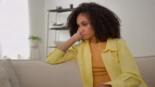 Woman Sitting Contemplatively on Couch in Bright Interior