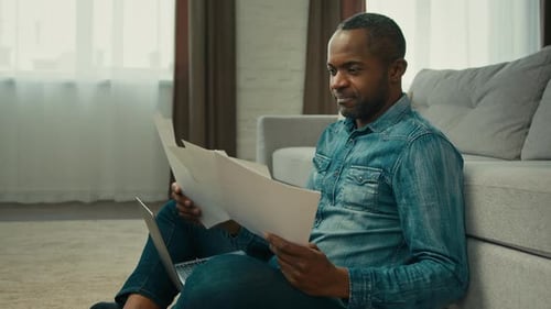 Man Analyzes Documents with Laptop at Home