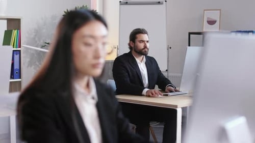 Man Working on Computer with Woman at Office
