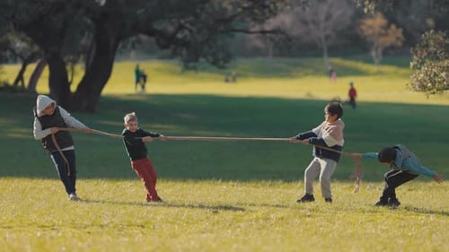 Niños jugando un juego competitivo de tira y afloja en el parque