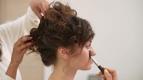Nahaufnahme von Elegance: Junge Frau, die sich von einem Visagisten im Schönheitsstudio schminkt