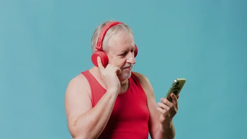 Comical Grandpa Enjoying Music on Earphones in Studio Shot