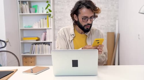 Young Adult Talking on Smartphone in Home Office