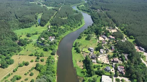 AERIAL: High Altitude Flight Over River Bank with Forest and Houses on Each Side of River