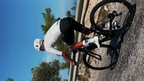Male cyclist riding road bicycle at sunny summer day. Vertical video.