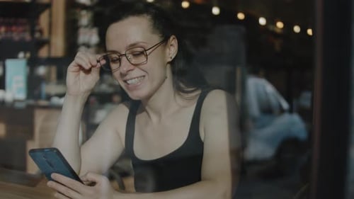 Close Up of Woman Holding Cell Telephone in a Caffe Talking to a Friend on Mobile Phone During