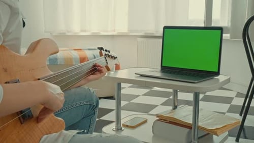 Musician Playing Bass Guitar with Green Screen Laptop