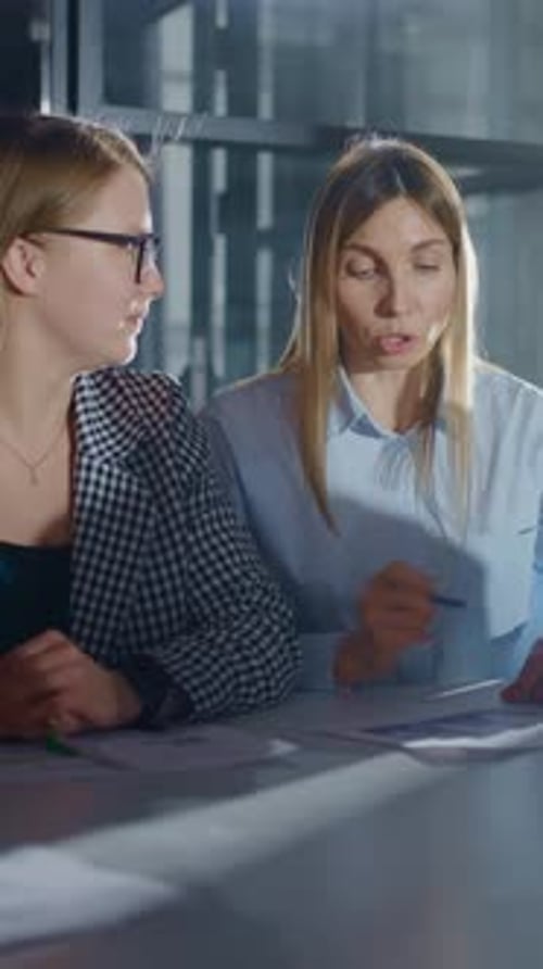Berufstätige Frauen arbeiten am Schreibtisch zusammen, während sie Geschäftsdokumente analysieren