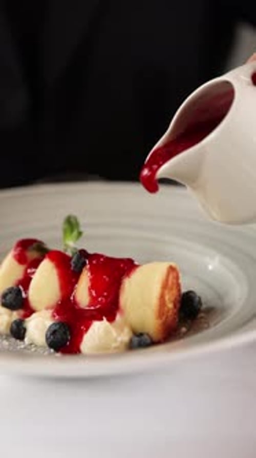 Pouring Berry Sauce Over Sweet Syrniki Dessert