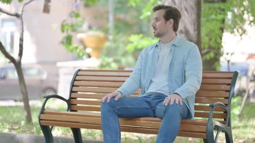 Man Sitting on Park Bench Looking Around