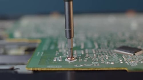 Screwdriver Tightening Screw on Green Circuit Board