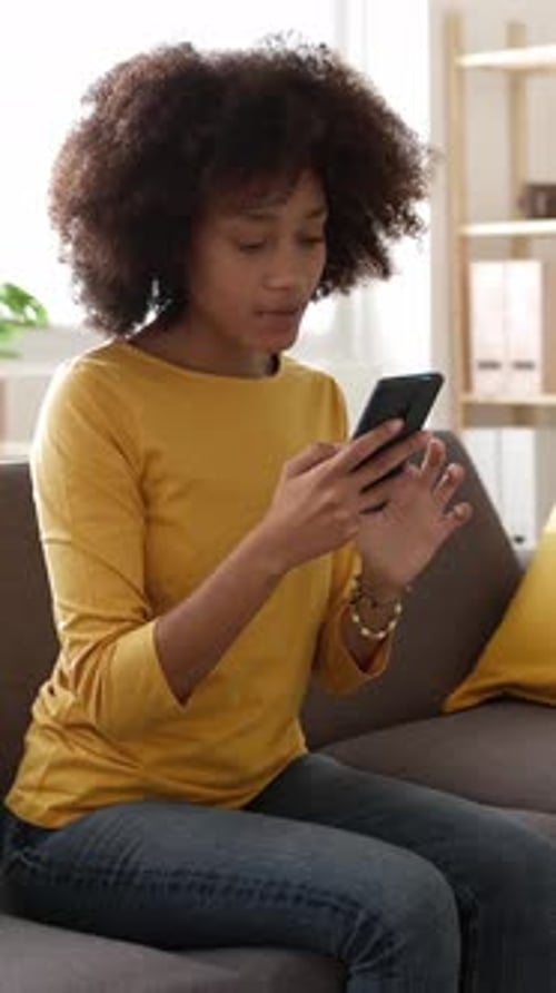 Woman on Sofa Uses Smartphone with Concerned Expression