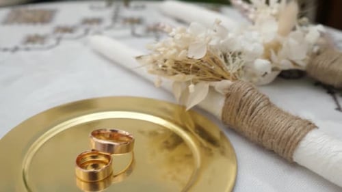 Golden Wedding Rings on Plate with Decorative Candle