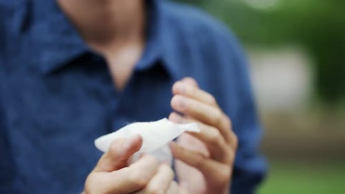 A Young Man Wipes His Hands with Napkins