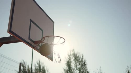 Der Basketballball trifft im Sonnenlicht auf den Reifen und bringt die Ketten zum Schwingen des Bogenschusses