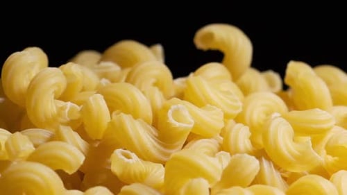 Raw macaroni pasta falls gracefully in stunning slow motion.