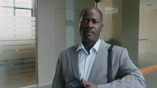Portrait of Black Businessman in Office Hallway with Phone in Hand