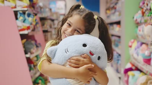 In a Bustling Toy Store an Enchanting Little Girl Joyfully Embraces a Plush Toy with Adorable