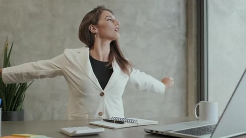 Woman Stretching at Desk in Office Environment