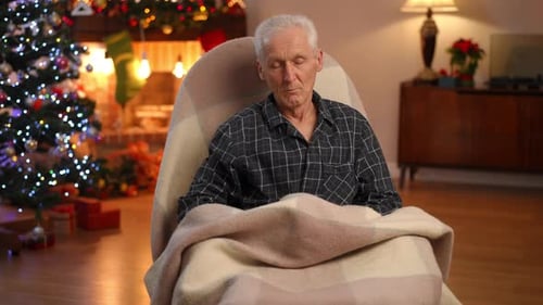 Tired Senior Man Sitting in Rocking Chair Falling Asleep Covering with Blanket As Lights Turn Off in