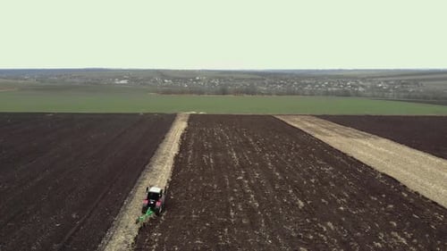 Red tractor plowing the field in Ukraine