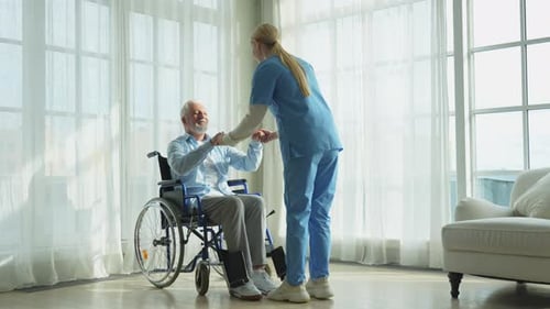 Rehabilitation Healthcare Physiotherapist Nurse Helps Old Man Patient in Wheelchair Stand Up Walking
