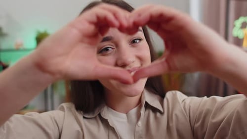 Young Woman Makes Heart Shape with Hands