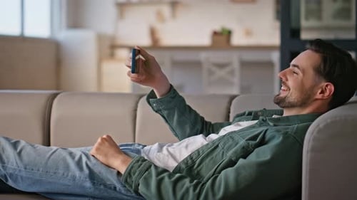 Man Relaxes on Couch Using Phone with Green Screen