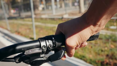 Point de vue en POV sur un vélo, gros plan d'une main sur un vélo, poignée d'une journée ensoleillée, mise en valeur