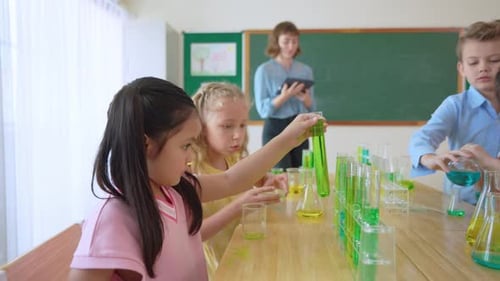 Adorable student learn with teacher in classroom at elementary school.