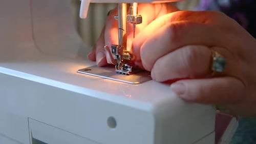 Nahaufnahme des Fadens von Schneiderhänden, der die Nähmaschine für die Arbeit vorbereitet
