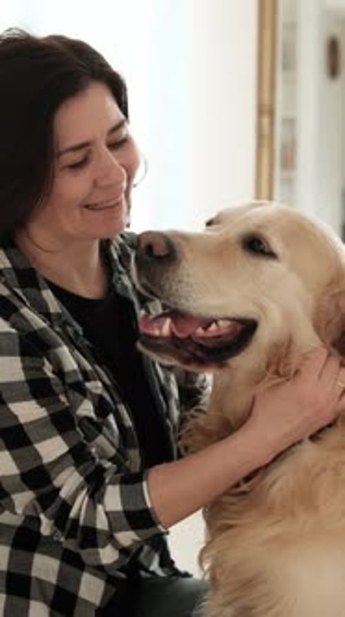 Woman Affectionately Petting Her Golden Retriever Dog Indoors