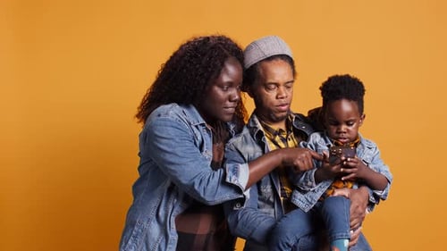 Loving Family Using a Smartphone Together on Orange