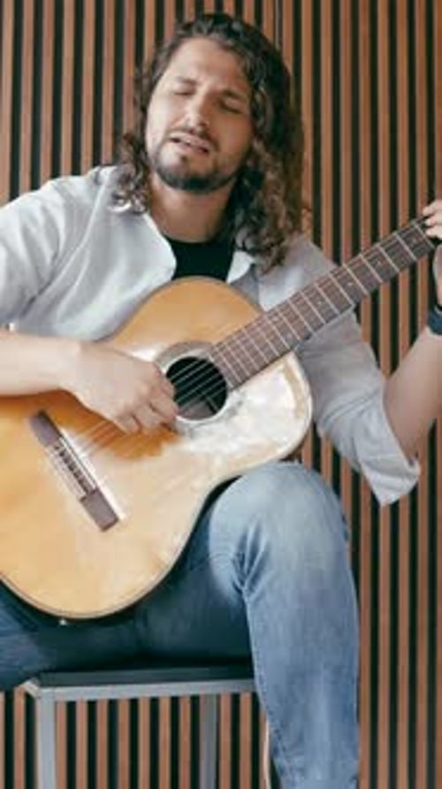 Man Plays Guitar and Sings Indoors Passionately