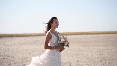 Happy Young Bride with Bouquet of Flowers Going at Desert Landscape Elegance Lady in Gorgeous