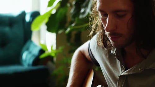 Man playing acoustic guitar inside the house during day
