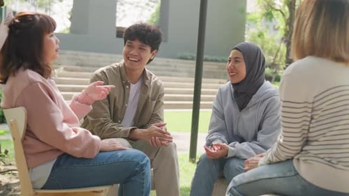 Small Asian group of people sit in a close circle and talk to a therapist in park.