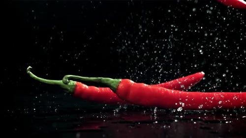 Chili Peppers fallen auf einen nassen schwarzen Tisch, gefilmt mit einer Hochgeschwindigkeitskamera mit 1000 Bildern pro Sekunde