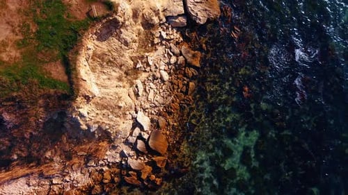 Blue clear water of the sea or ocean splashes to the rocks.