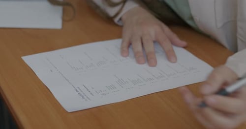 Closeup of Female Hand Writing English Test While Student Passing Examination in Classroom at Desk