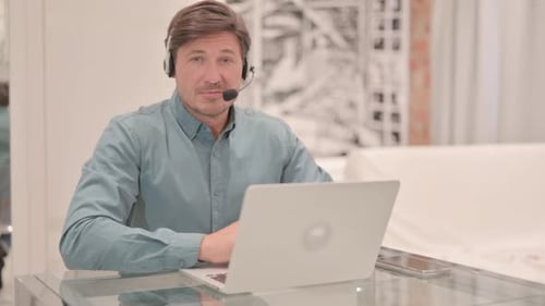 Mature Adult Man with Headset Smiling at Camera in Call Center
