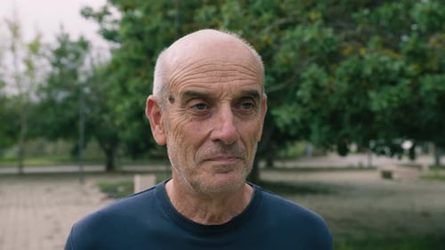 Elderly Man Makes A Hesitant Approving Face In The Park Near The Trees