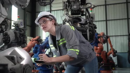 Un travailleur inspecte une chaîne de montage robotique dans une installation industrielle pendant la journée