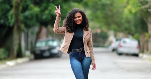 Pretty elegant black girl posing at camera smiling outside in street