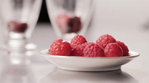 Hand Places Raspberries Into Dessert Glasses