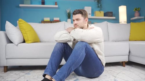 Distressed Man Sitting on Floor in Living Room