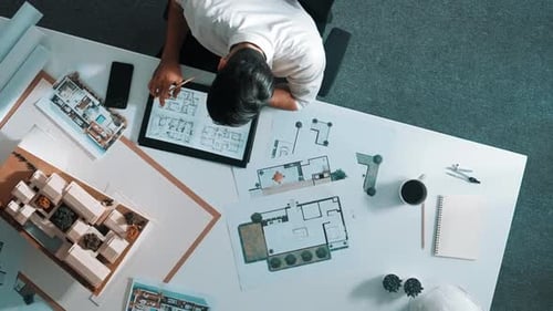 Ansicht von oben auf einen intelligenten Geschäftsmann, der ein Tablet verwendet, um das Hausdesign zu planen. Ernährung.