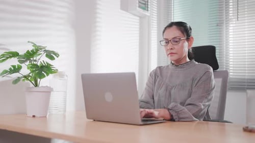 Woman Working on Laptop at Bright Office Desk