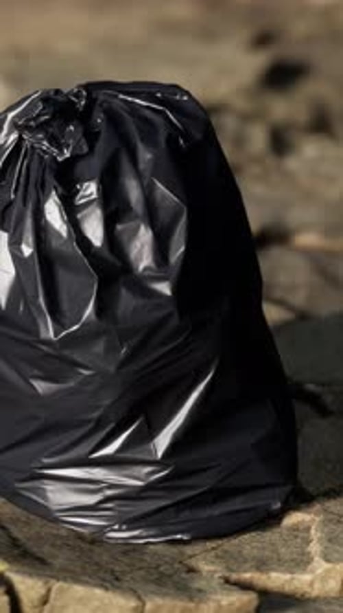 Black Trash Bag Lay on a Rocky Beach