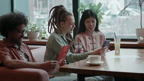 Group of Friends in Restaurant Talking, Laughing and Looking at Menu